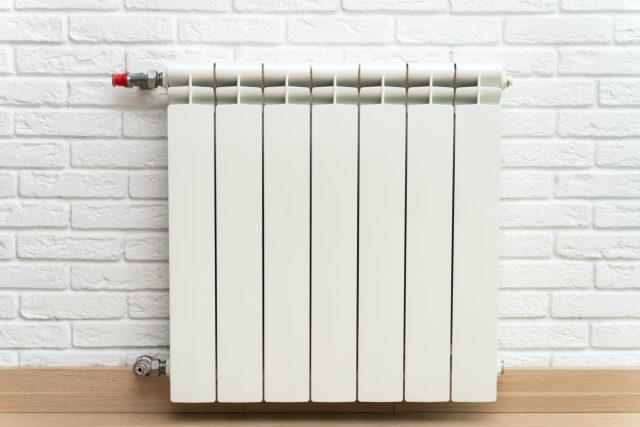 white-central-heating-radiator-on-white-brick-wall