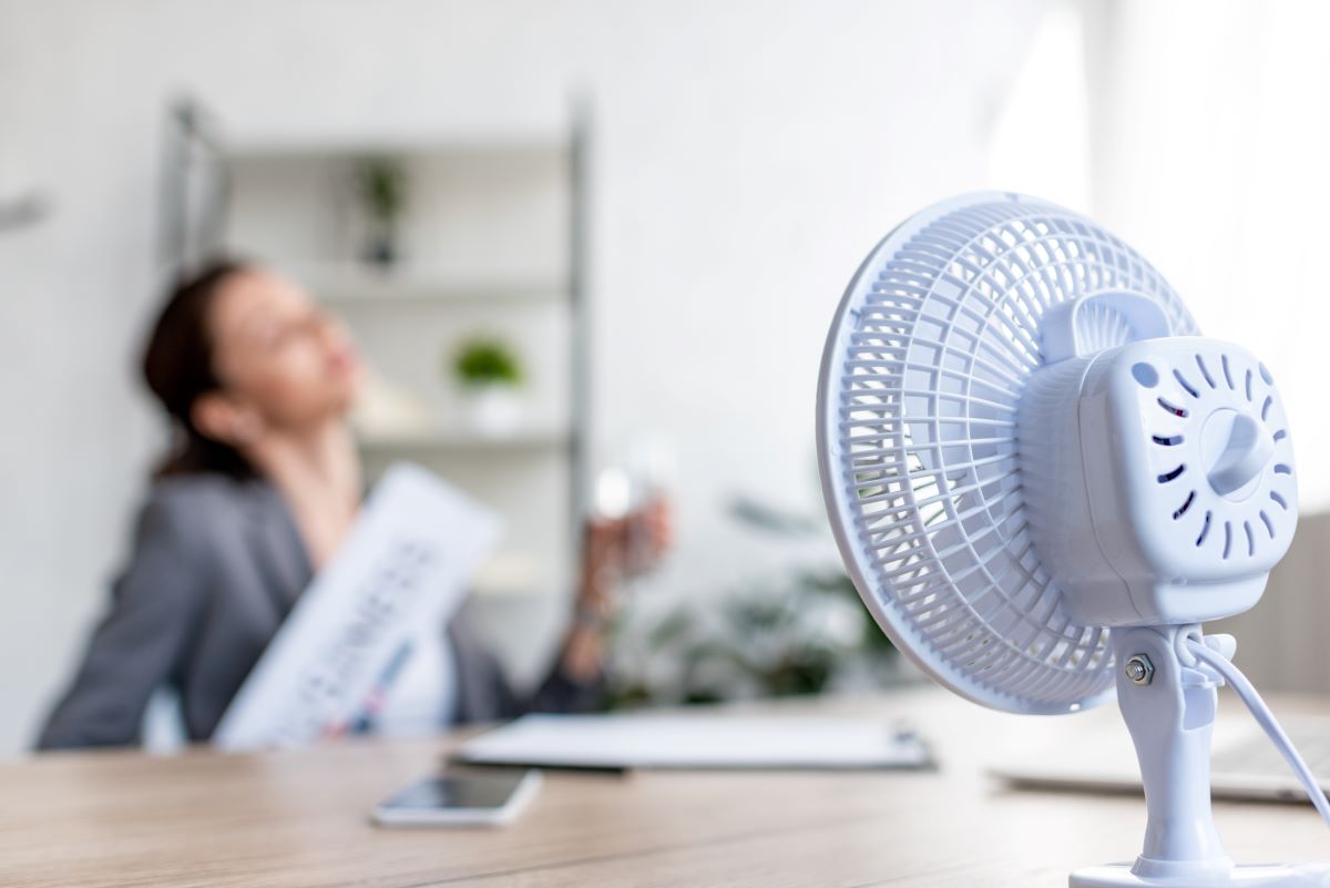 businesswoman-suffering-from-heat-while-sitting-near-fan